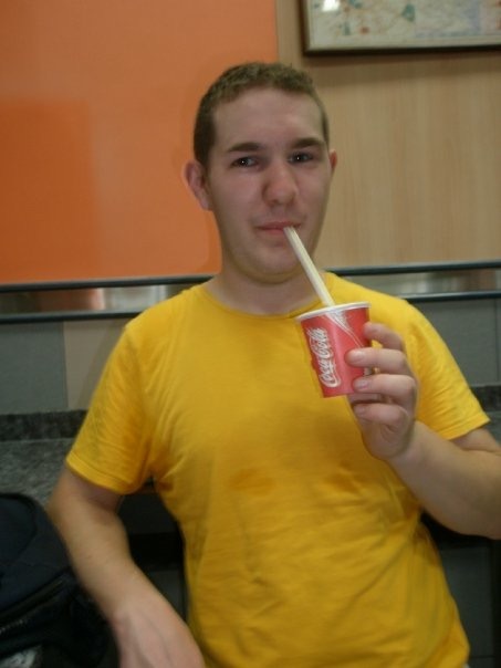 Karl in a yellow t-short drinks from a straw in a small Coca-Cola cup in McDonald's India