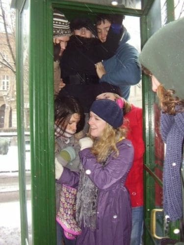 6 young people squeezed into a green phone box in Budapest, Hungary