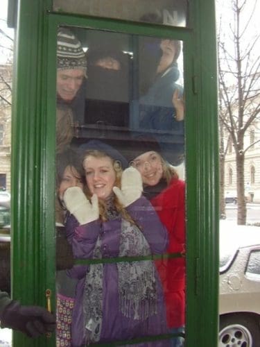 6 young people squeezed into a green phone box with the glass door closed in Budapest, Hungary