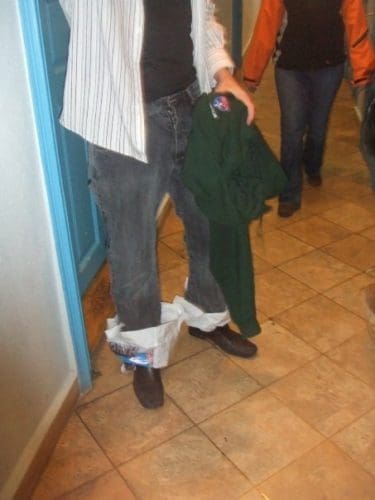 a man wearing grey jeans with plastic bags over socks, and black shoes
