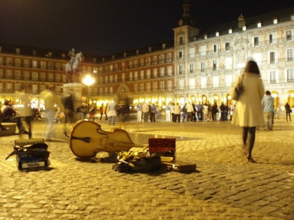 Instruments from street performers sit on the cobbles of Plaza Mayor at night in Madrid, Spain