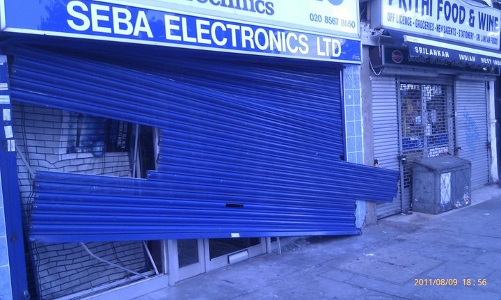 damaged blue shutters of an electronics shop in West Ealing, London