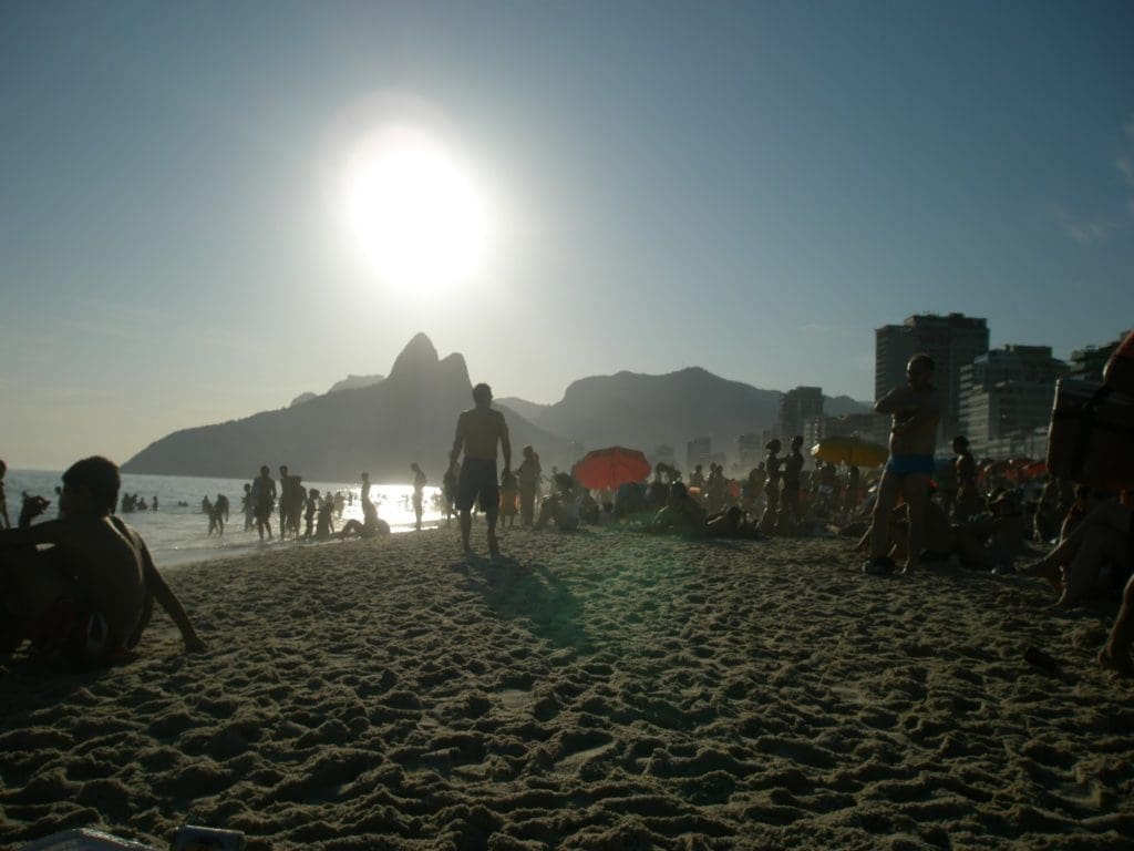 Afternoon silhouettes of people on Ipanema Beach, with Sugarloaf Mountain in the background, Rio de Janeiro, Brazil