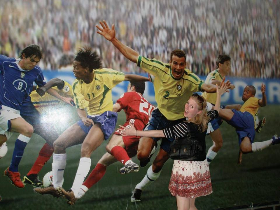 Rosie pretends to hug a footballers photo at the Maracana Stadium, Rio de Janeiro
