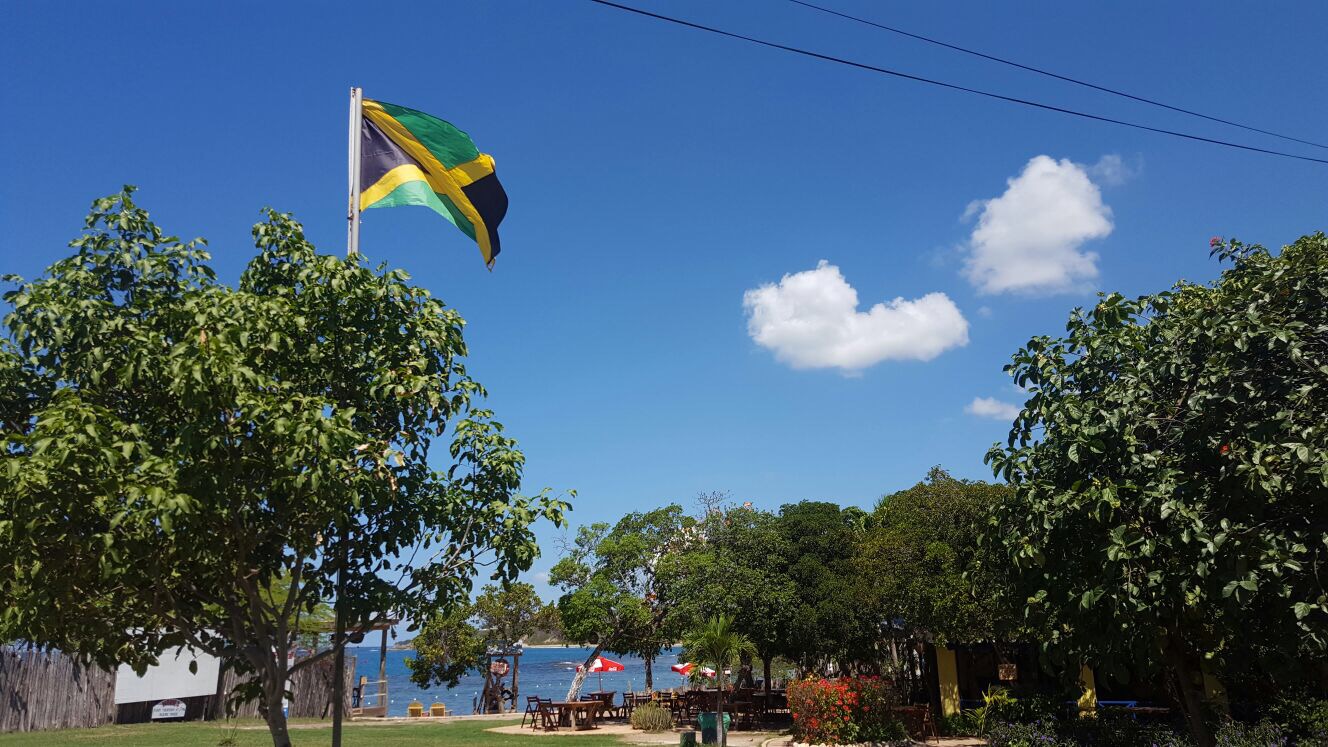 The Jamaican flag flies in a blue sky above Jack Sprats bar in Treasure Beach, Jamaica