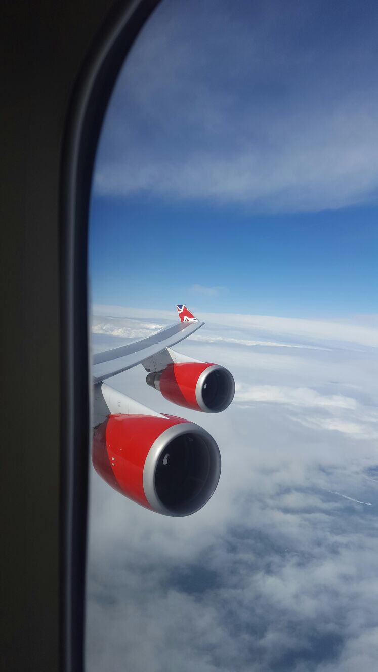 A view from the window of 2 red engines a the wing of a Virgin Atlantic Boeing 747 plane