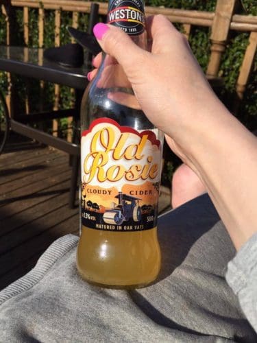 Rosie holds a 500ml bottle of Westons Old Rosie Cloudy Cider