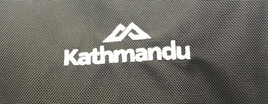 Kathmandu logo in white on a black Litehaul 38L backpack
