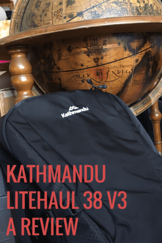 a black Kathmandu Litehaul 38 V3 backpack leans against a wooden globe bar. Overlaid red text reads 'Kathmandu Litehaul 38 V3 A Review'