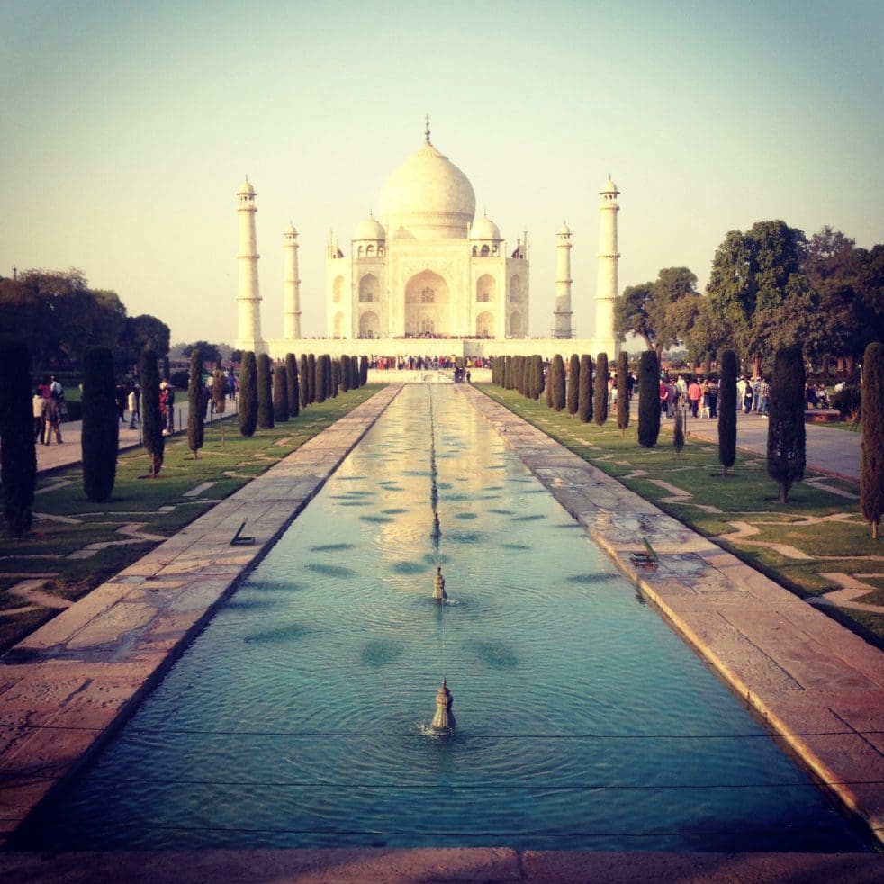 A photo of the Taj Mahal in the background through the gardens with pool leading up to it