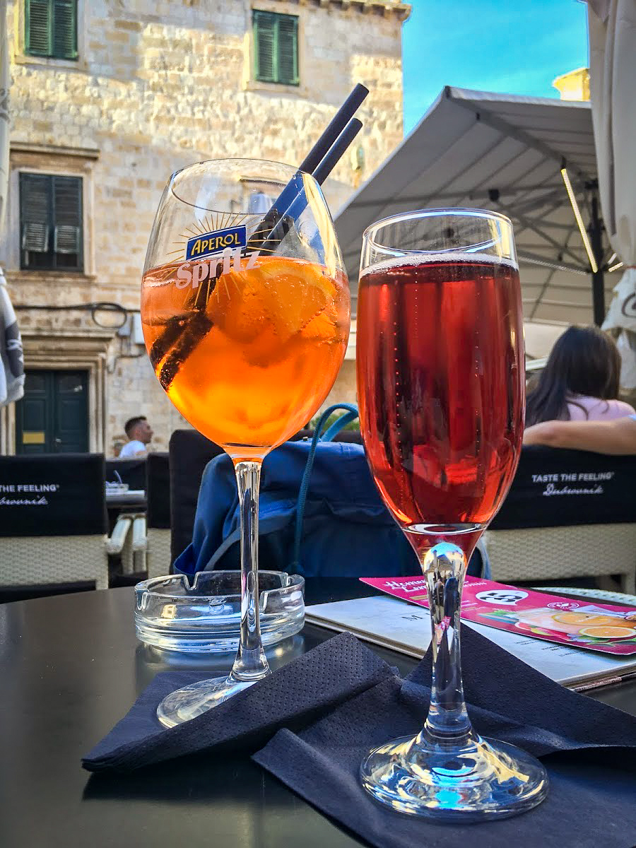 A glass of Aperol Spritz and a champagne flute with a red bubbly drink in Dubrovnik, Croatia