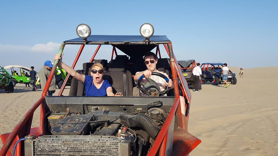 Rosie about to scream as Karl looks mischevious behind the wheel of a red dune buggy in the desert outside Huacachina, Peru