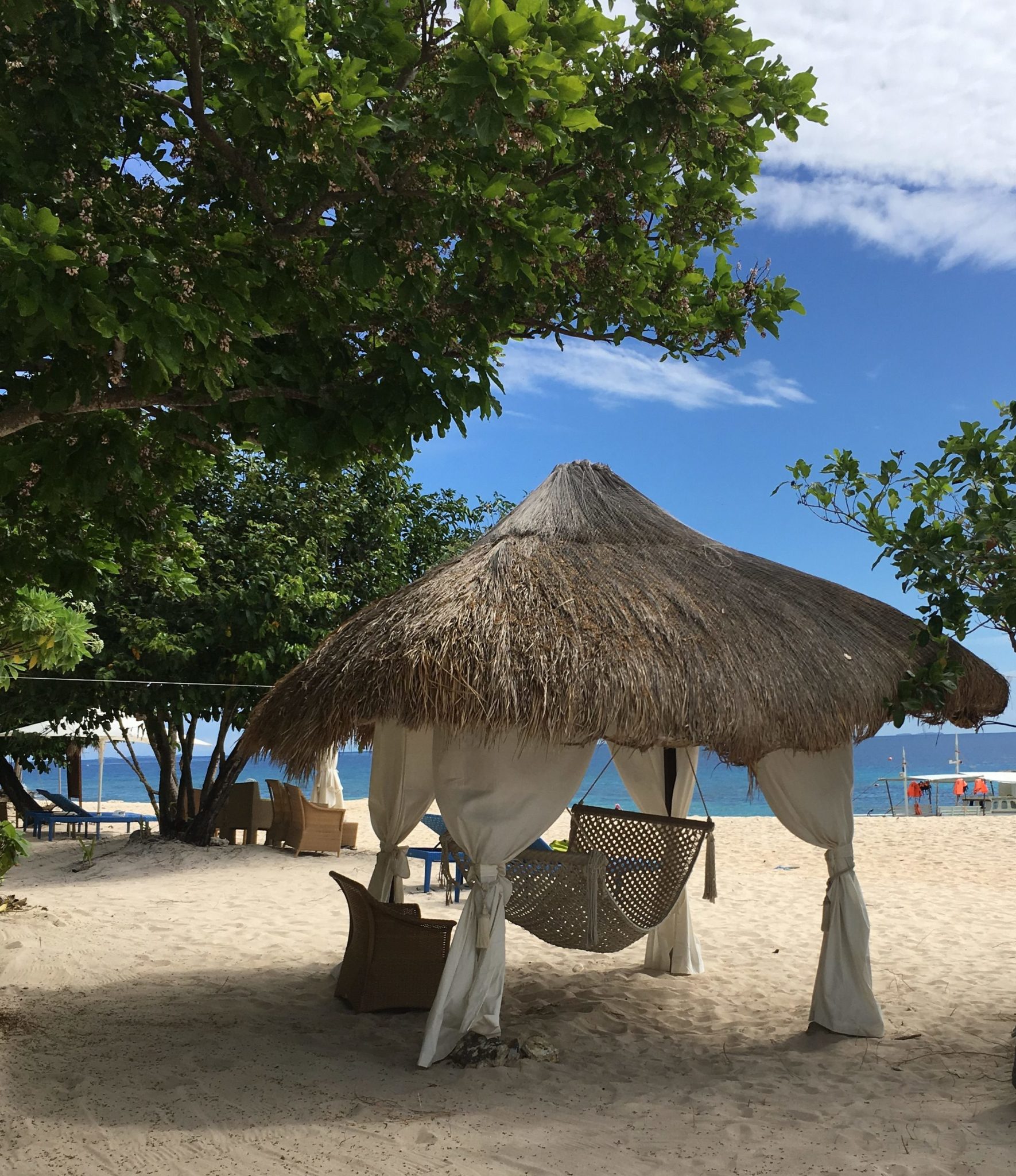 a hammock under a palm roofed pagoda on the white sand beach at Club Paradise Palawan