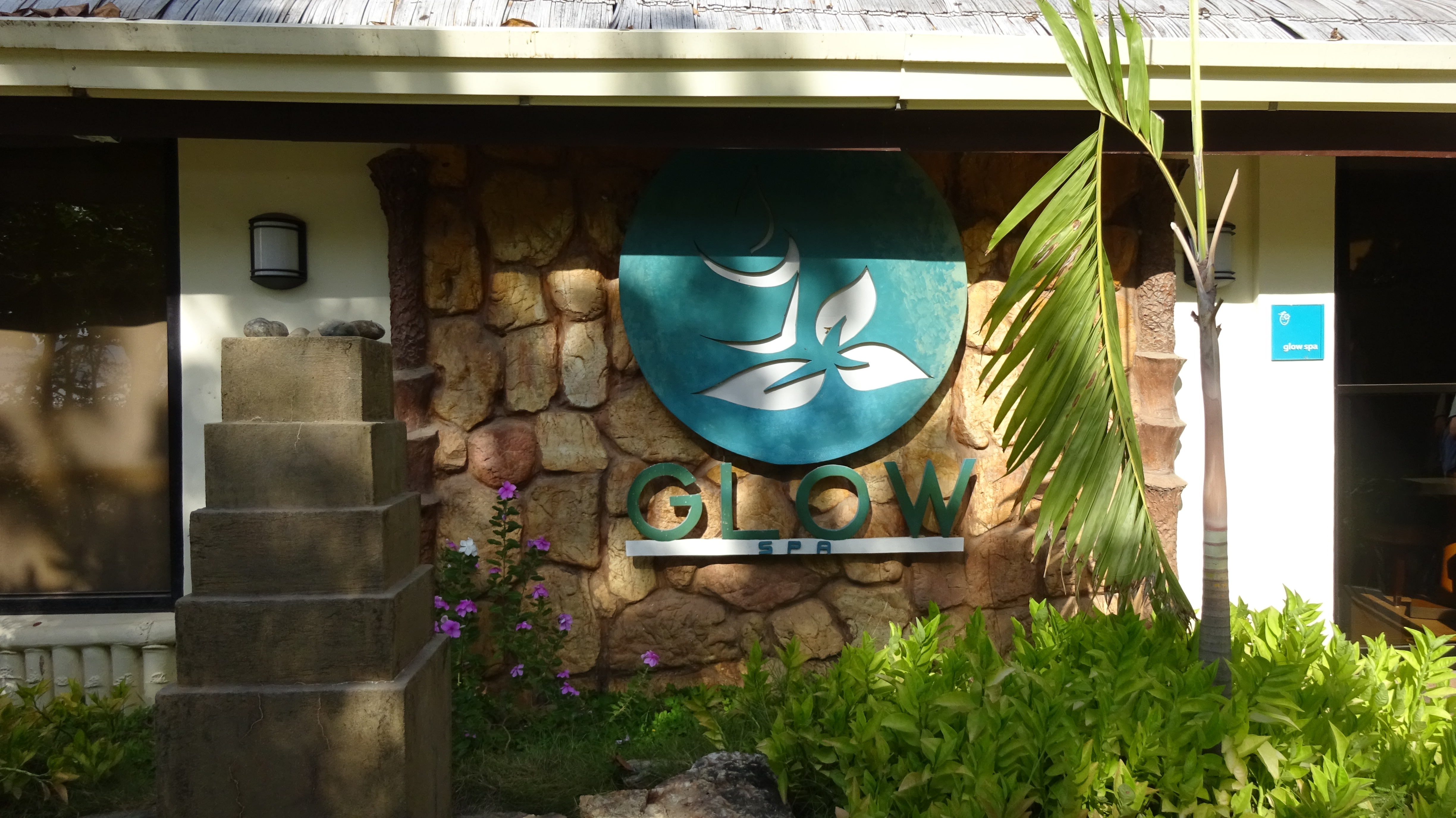 Glow Spa logo and sign with bushes and flowers in the foreground, Club Paradise Palawan