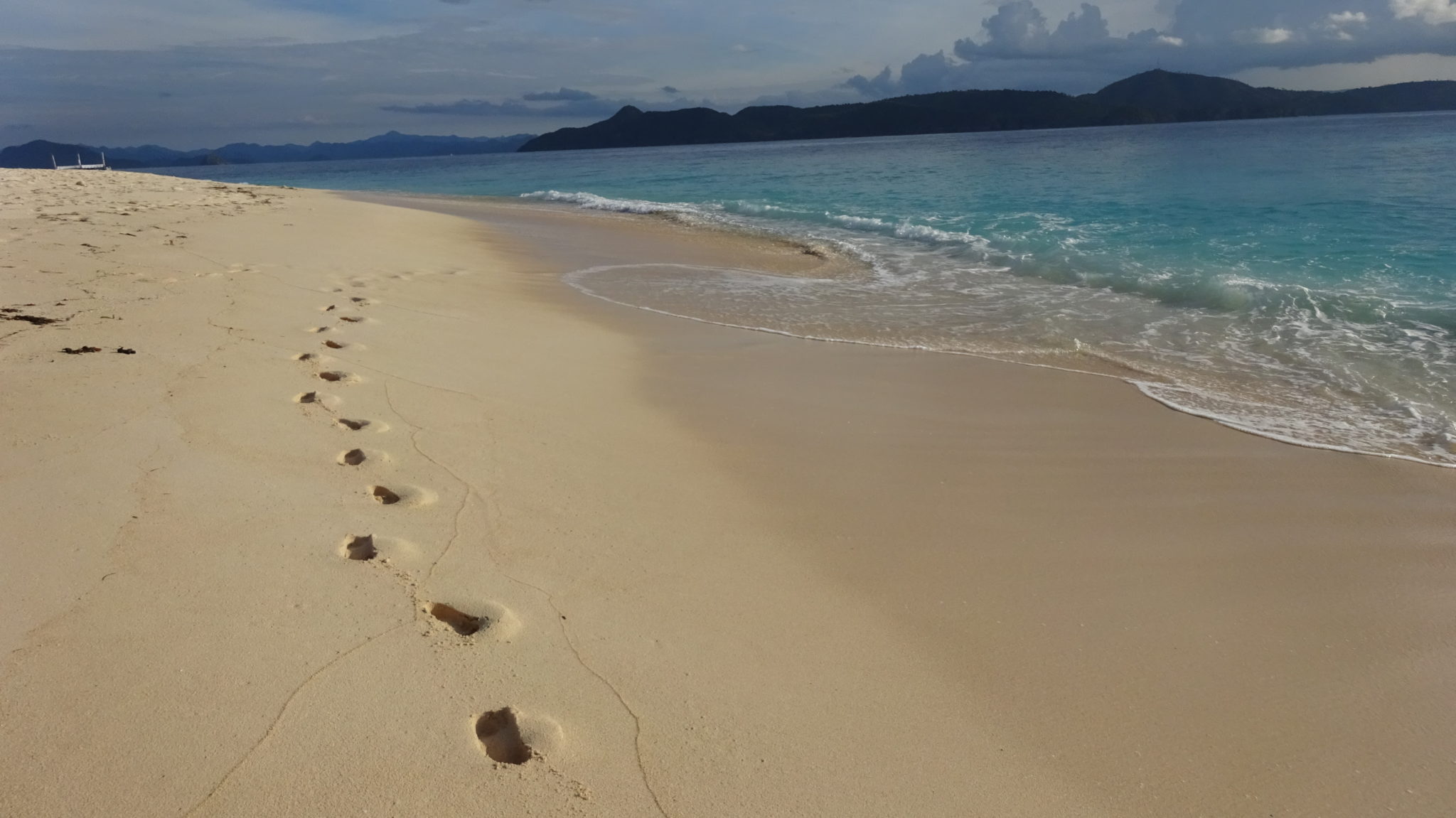 footprints in the sandy beach next to the blue South China Sea