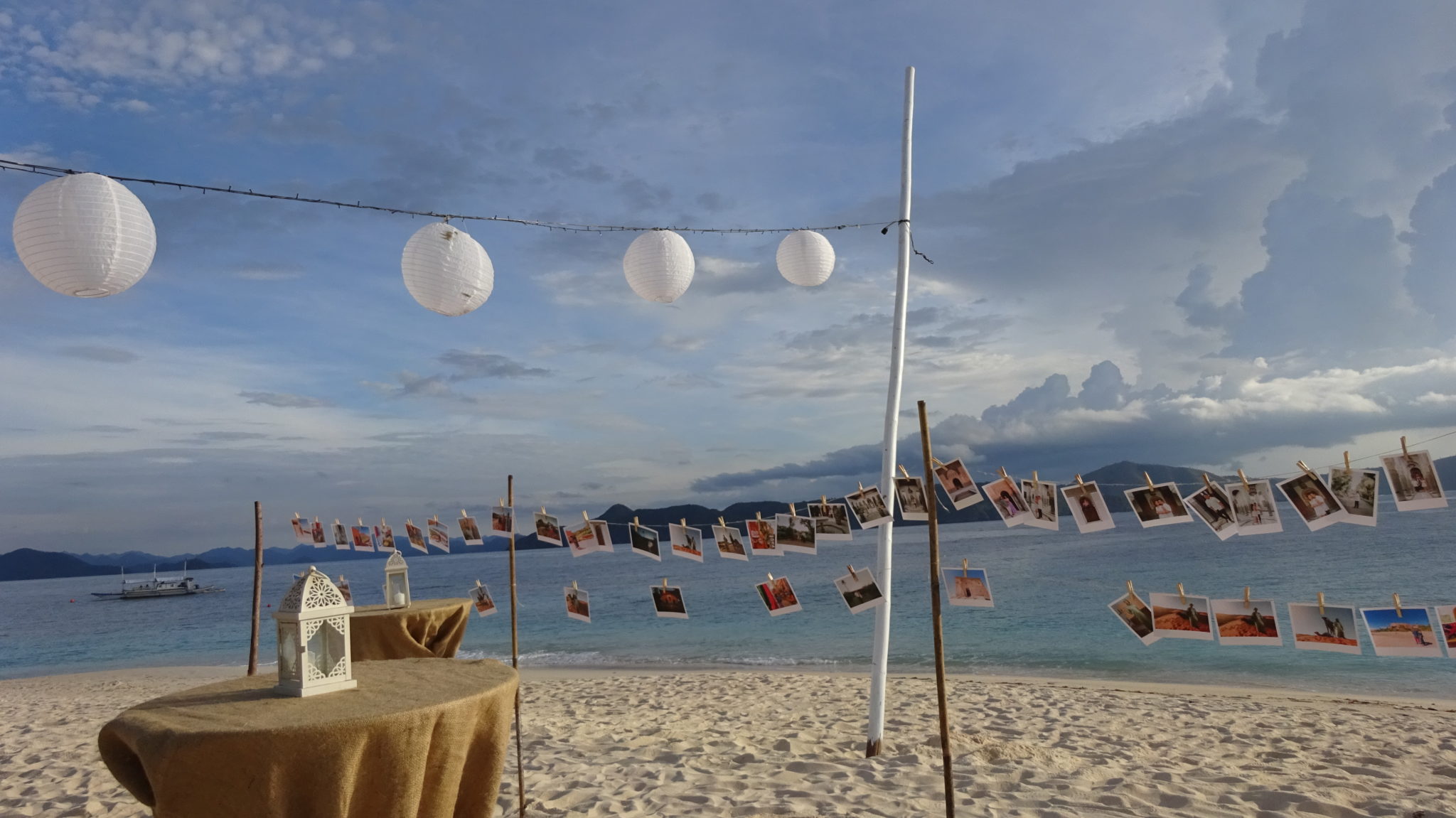 polaroid photos strung up for a wedding on the white sandy beach with the South China Sea in the background at Club Paradise Palawan