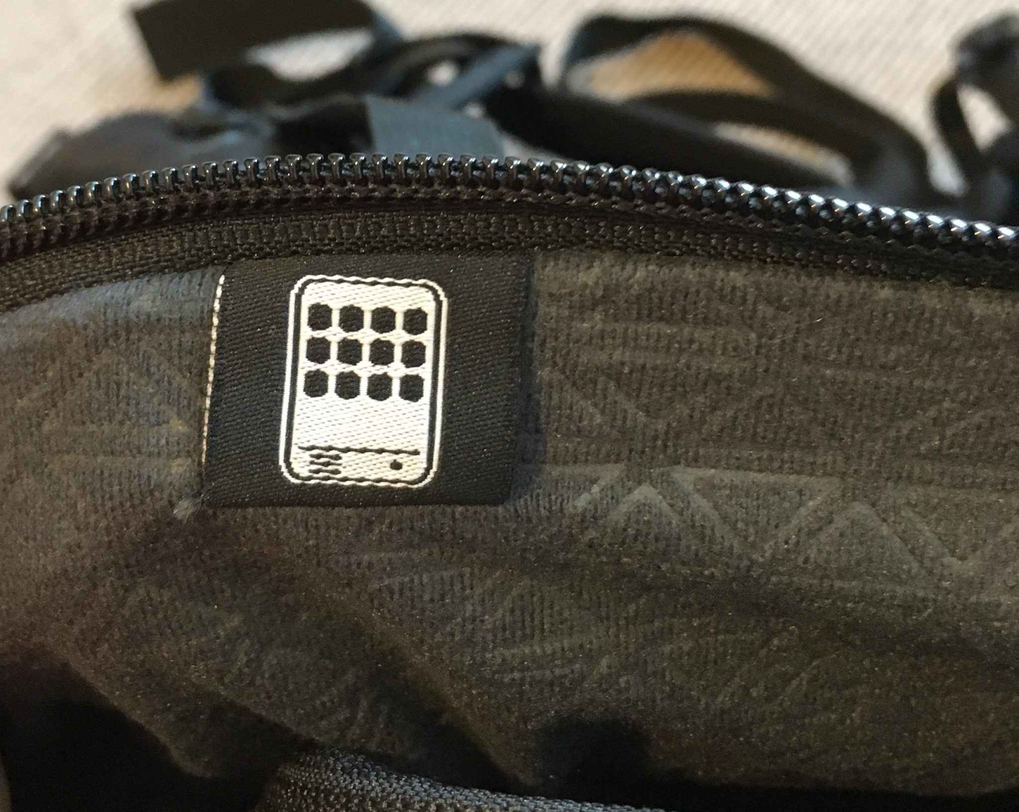 A close up of the tablet pocket on a black Kathmandu Litehaul 38L Backpack