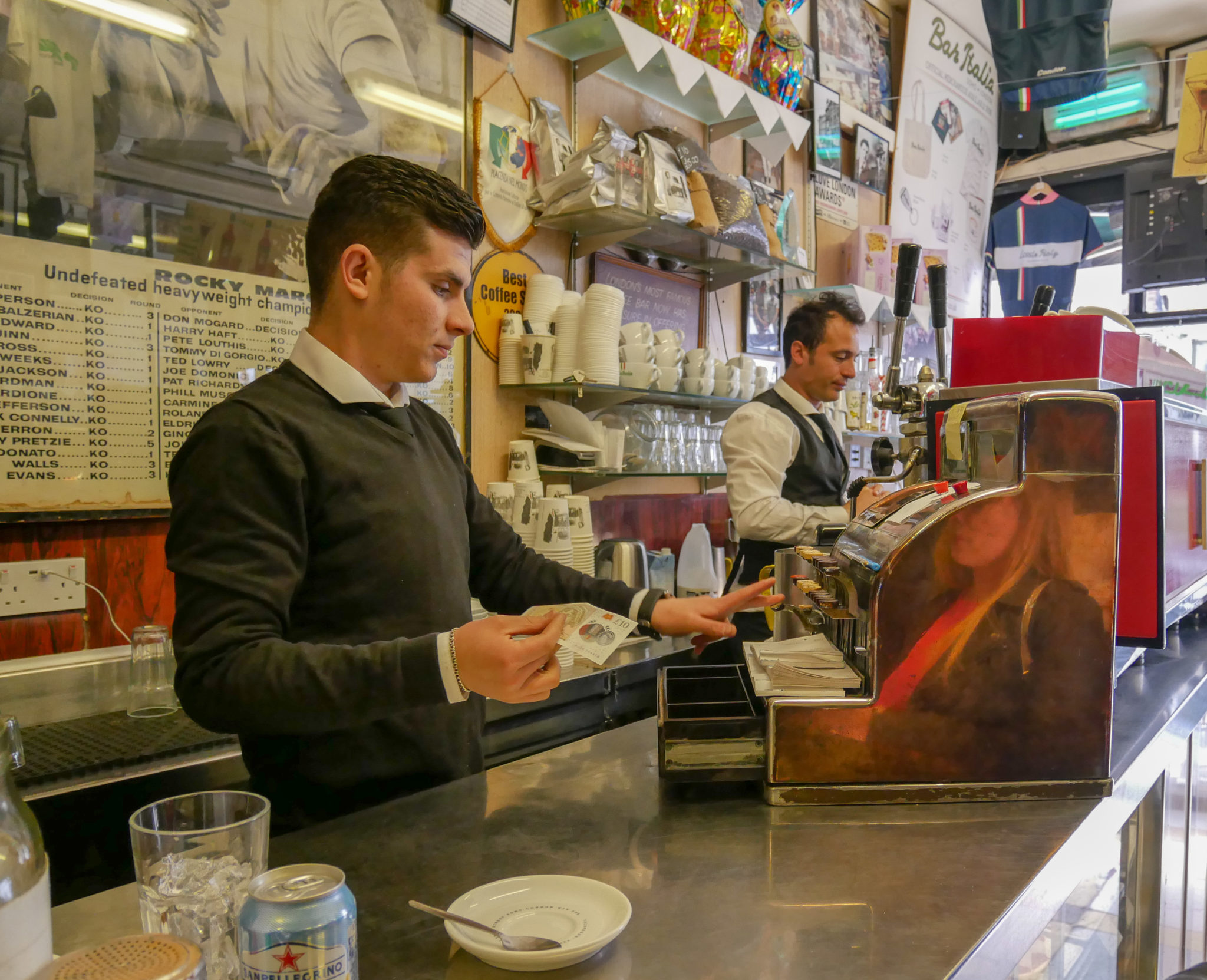 a server puts money into an old till on the counter at Bar Italia, Soho, London