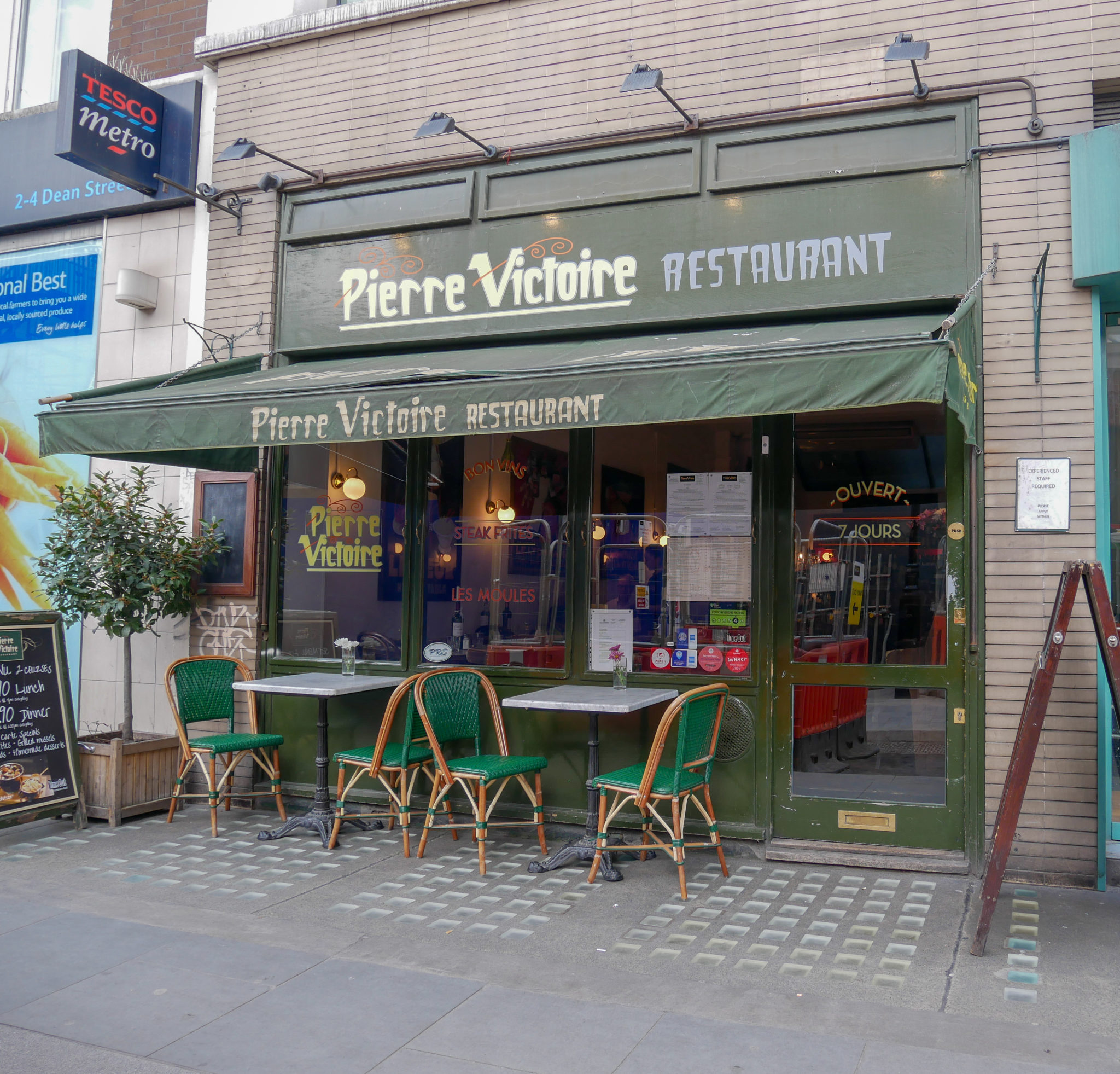 The green front of Pierre Victoire Restaurant with 2 tables outside, Soho, London