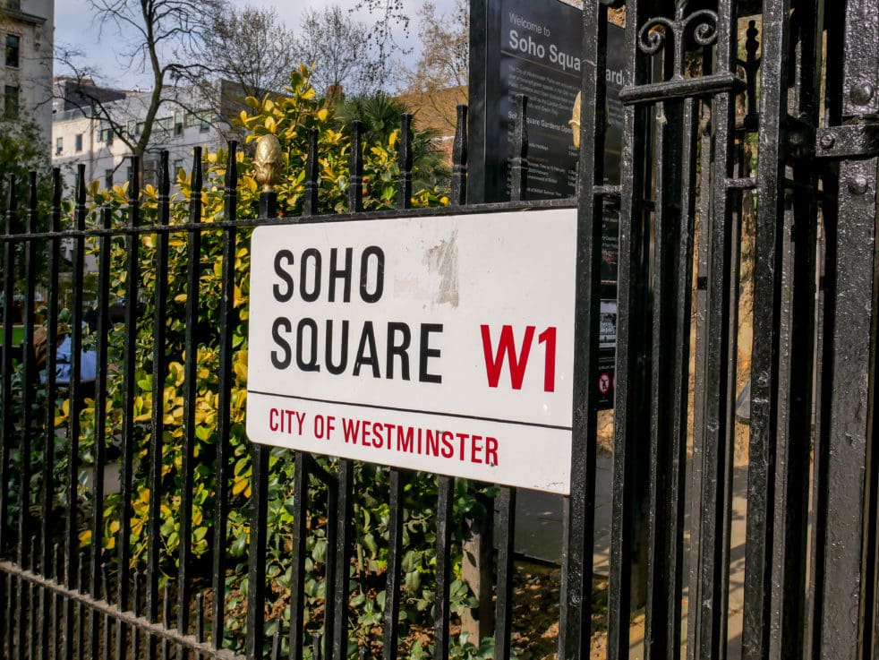 White City of Westminster street sign of Soho Square, W1 attached to black metal railings