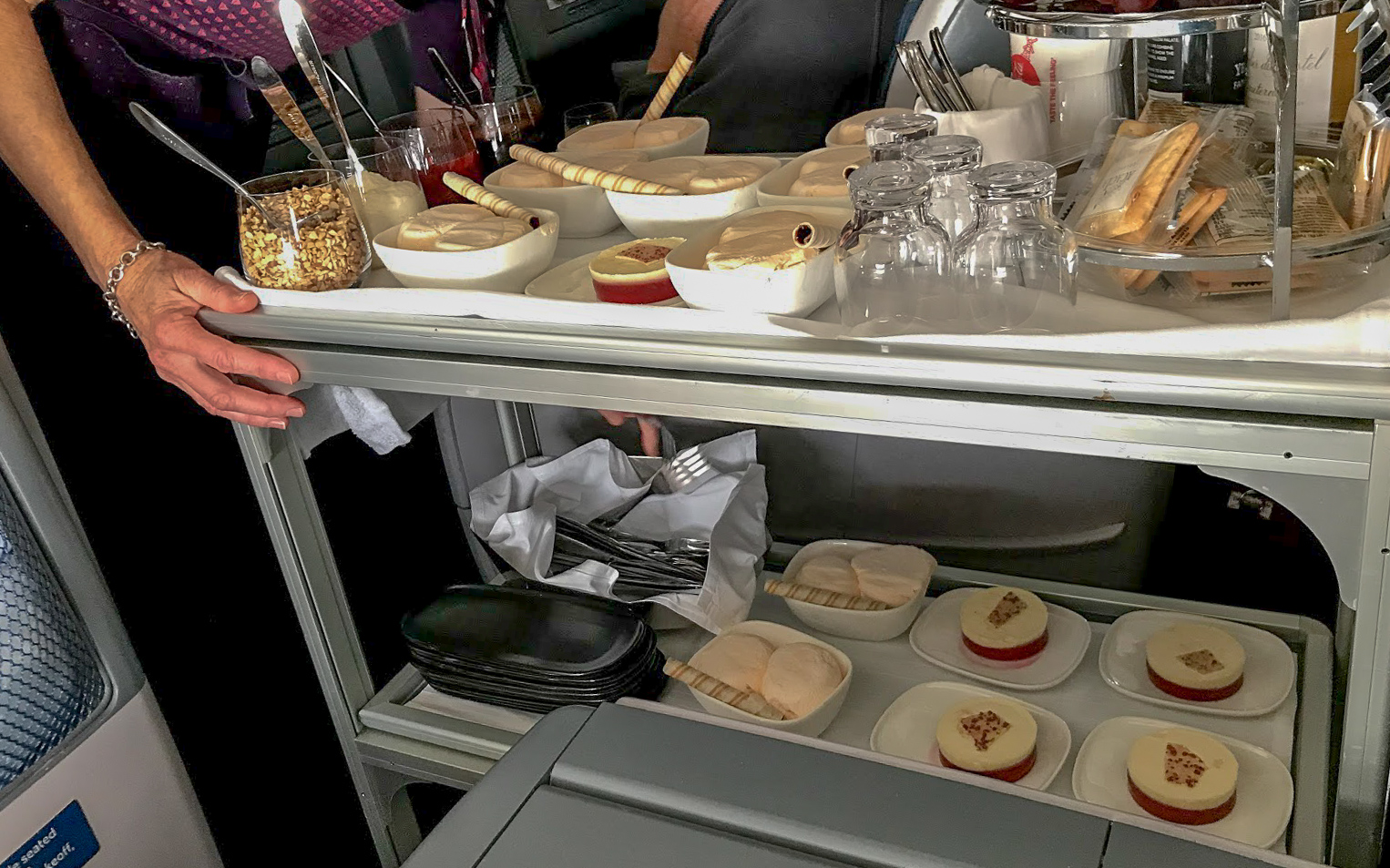 metal dessert trolley with bowls of ice cream and plates of cheescake on Delta One Delta Air Lines