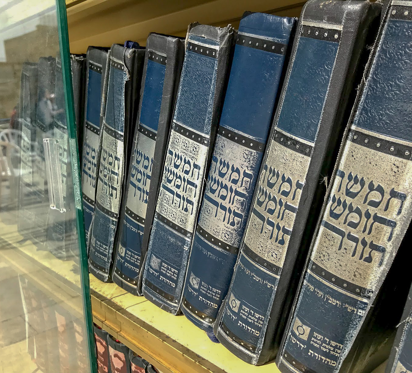 blue Hebrew hardback books on a bookshelf