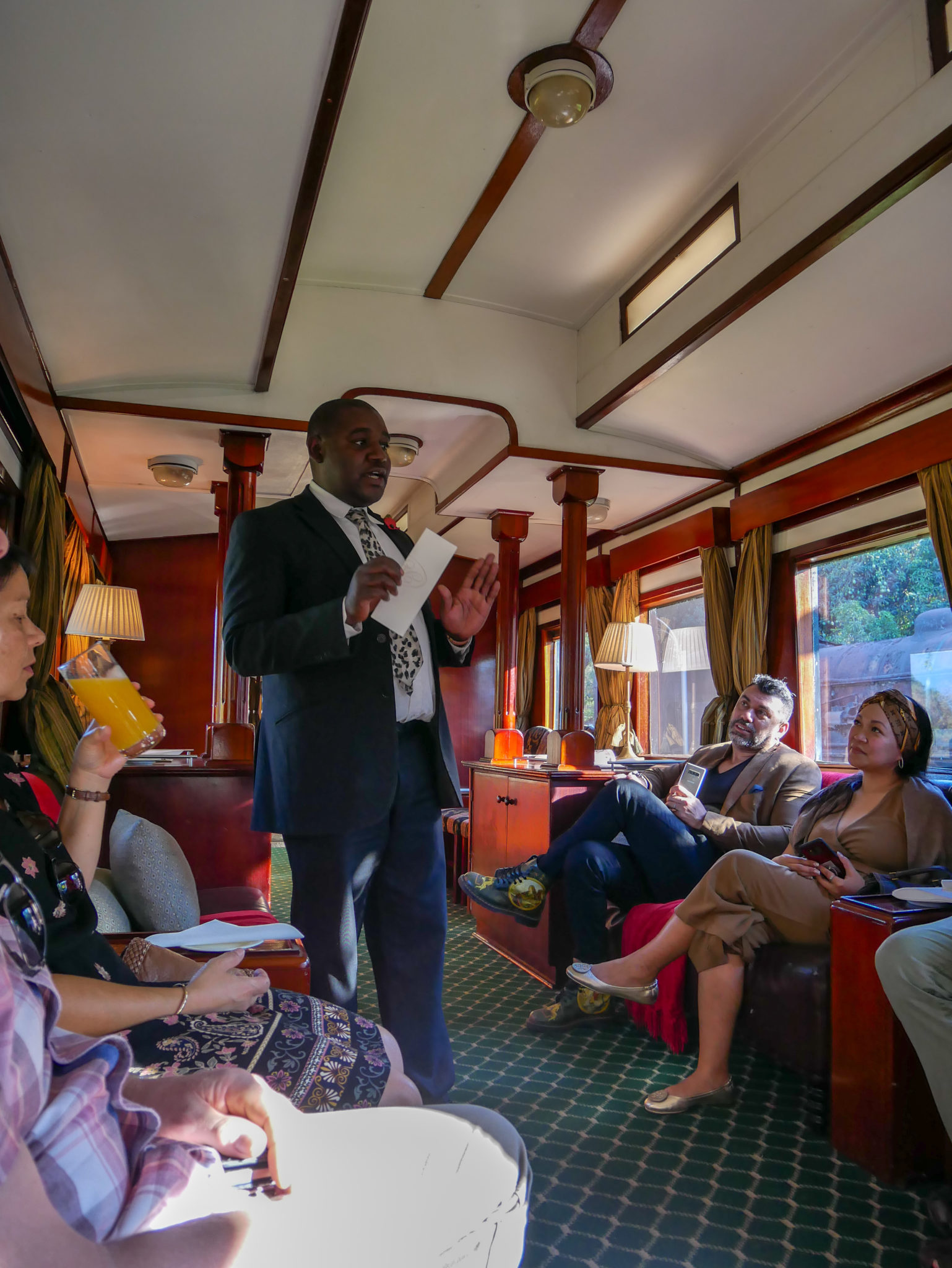 The host talks to guests in the Lounge Car of the Royal Livingstone Express train