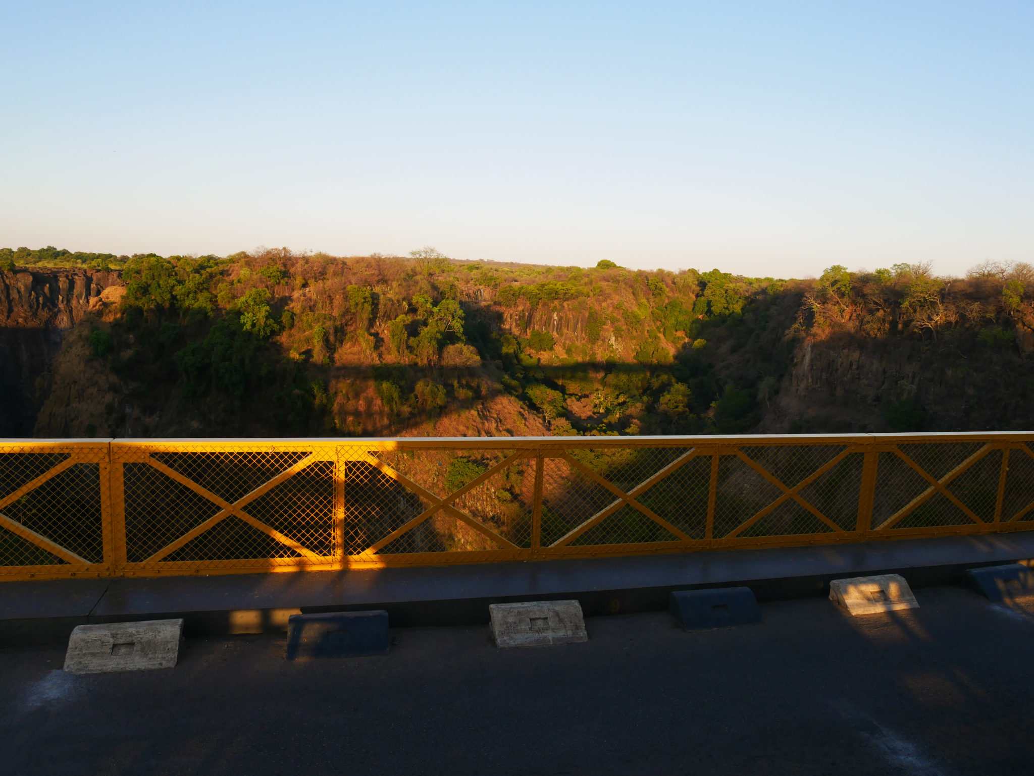 The setting sun casts a shadow of the Victoria Falls Bridge on the gorge