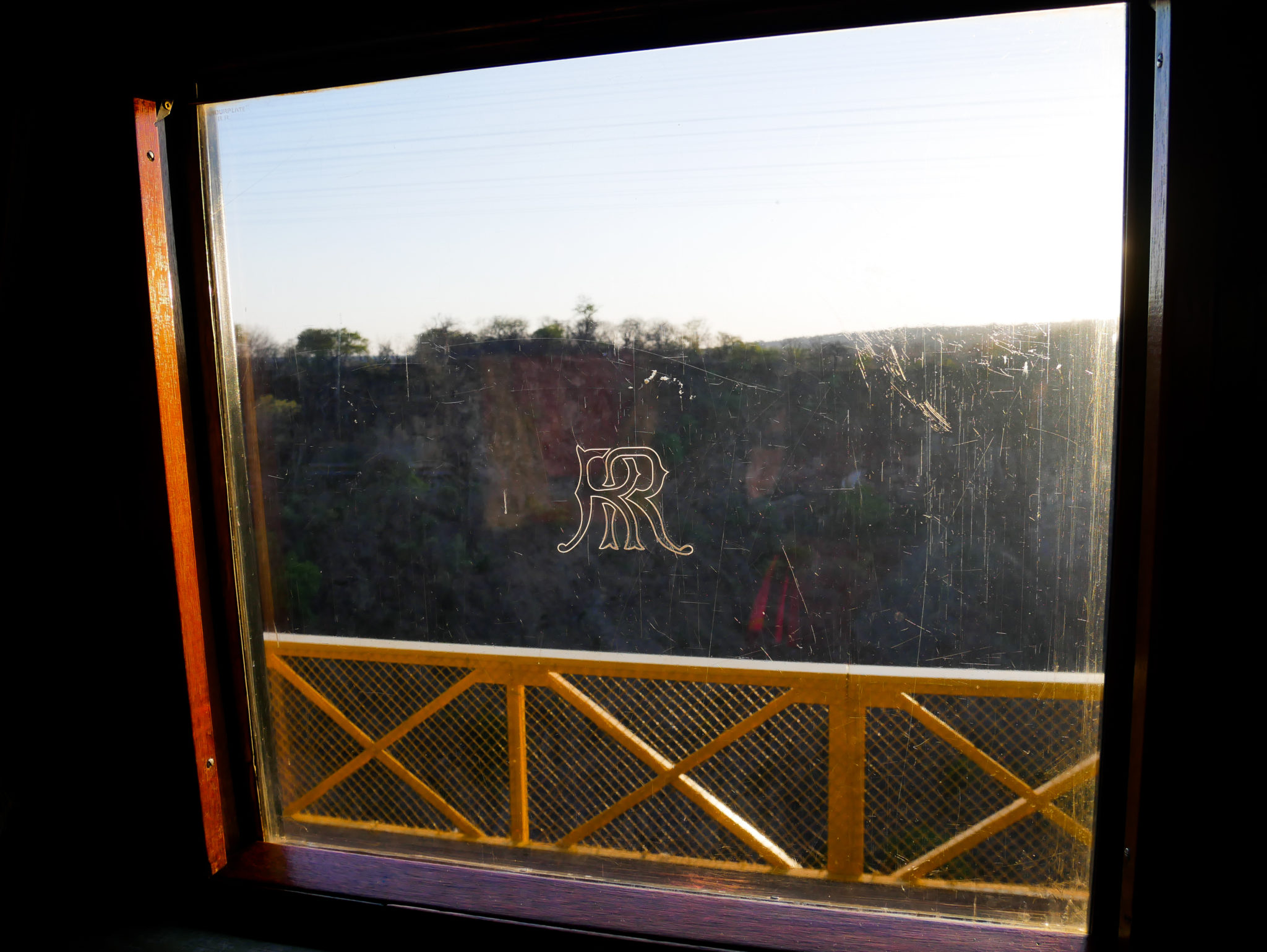 Evening sun shines through the Rovos Rail logo on the window of the Royal Livingstone Express train