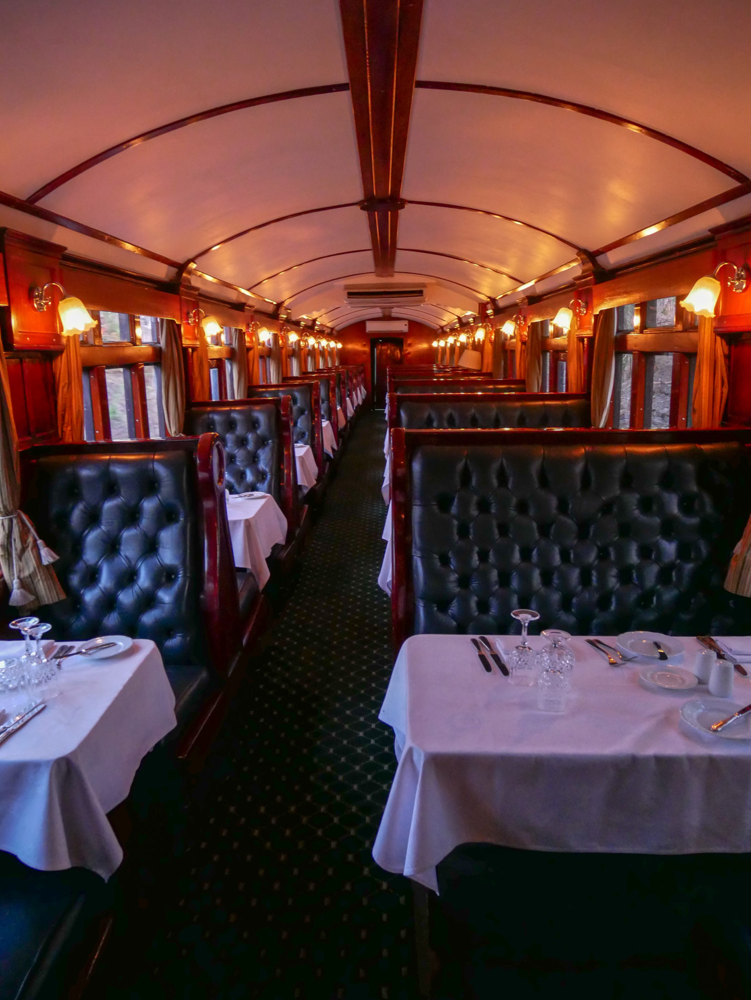 Tall black leather seats and white tablecloths in the Dining Car of the Royal Livingstone Express train