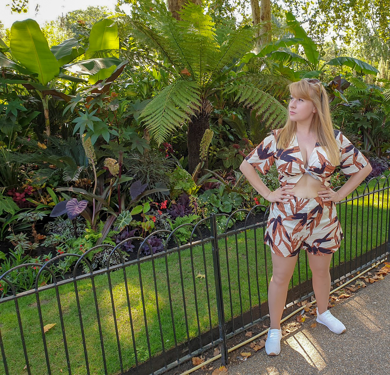 Rosie wearing brown leaf print shorts and top in front of a palm tree in St James's Park