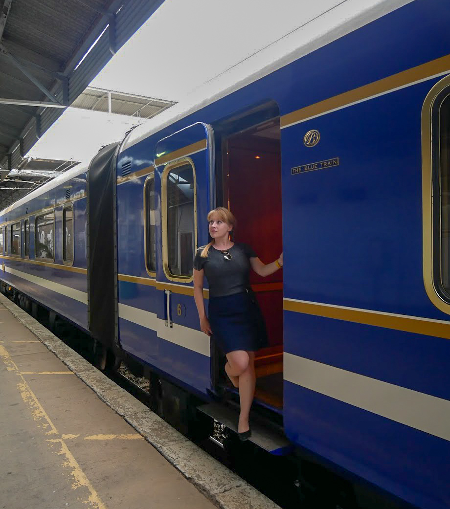 Rosie poses by the carriage door of the Blue Train in South Africa