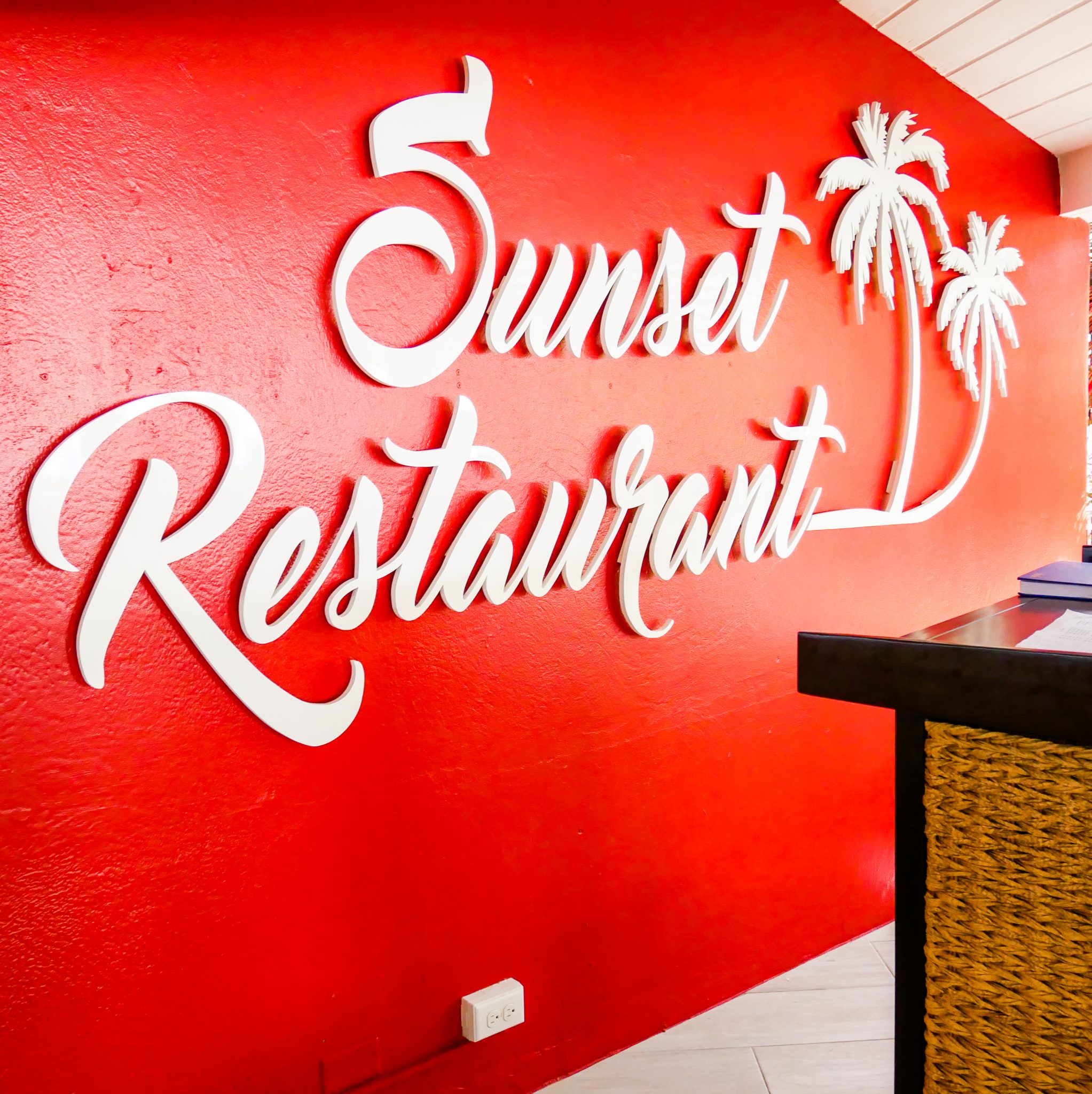 A bright red wall with the Sunset Restaurant logo in huge, raised white lettering