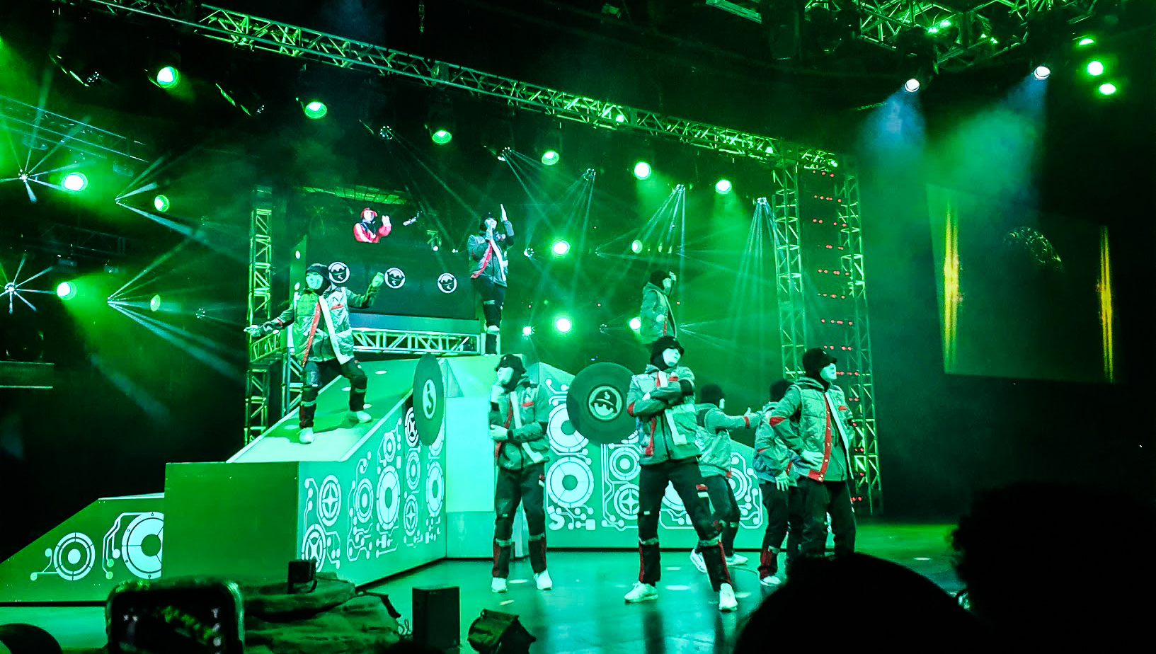 The whole crew is on stage, lit in bright green and the DJ rocks out