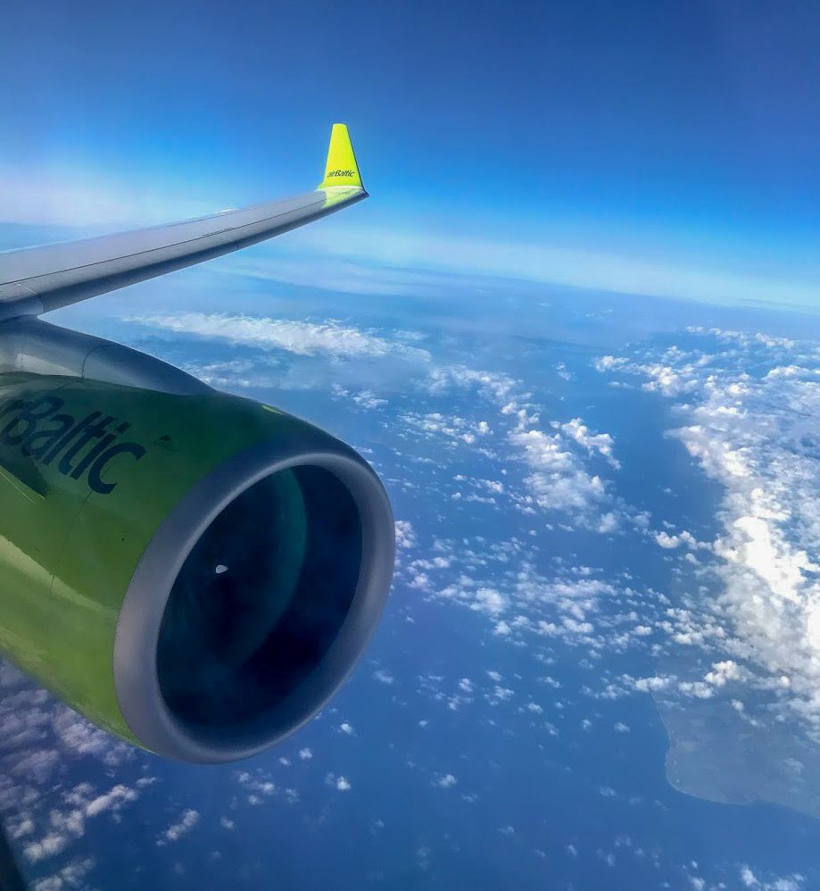 wing and engine of an airBaltic A220-300 above the clouds