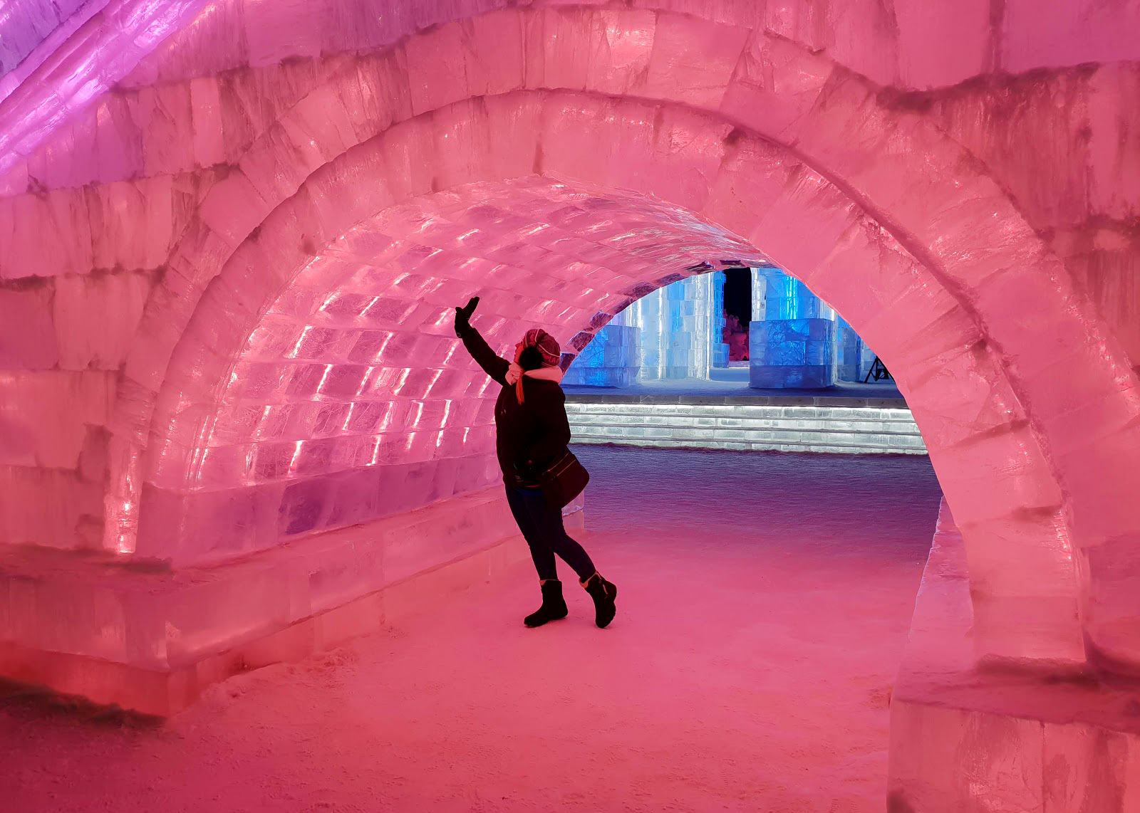 Rosie standing under an ice bridge lit in pink at Harbin Ice and Snow World