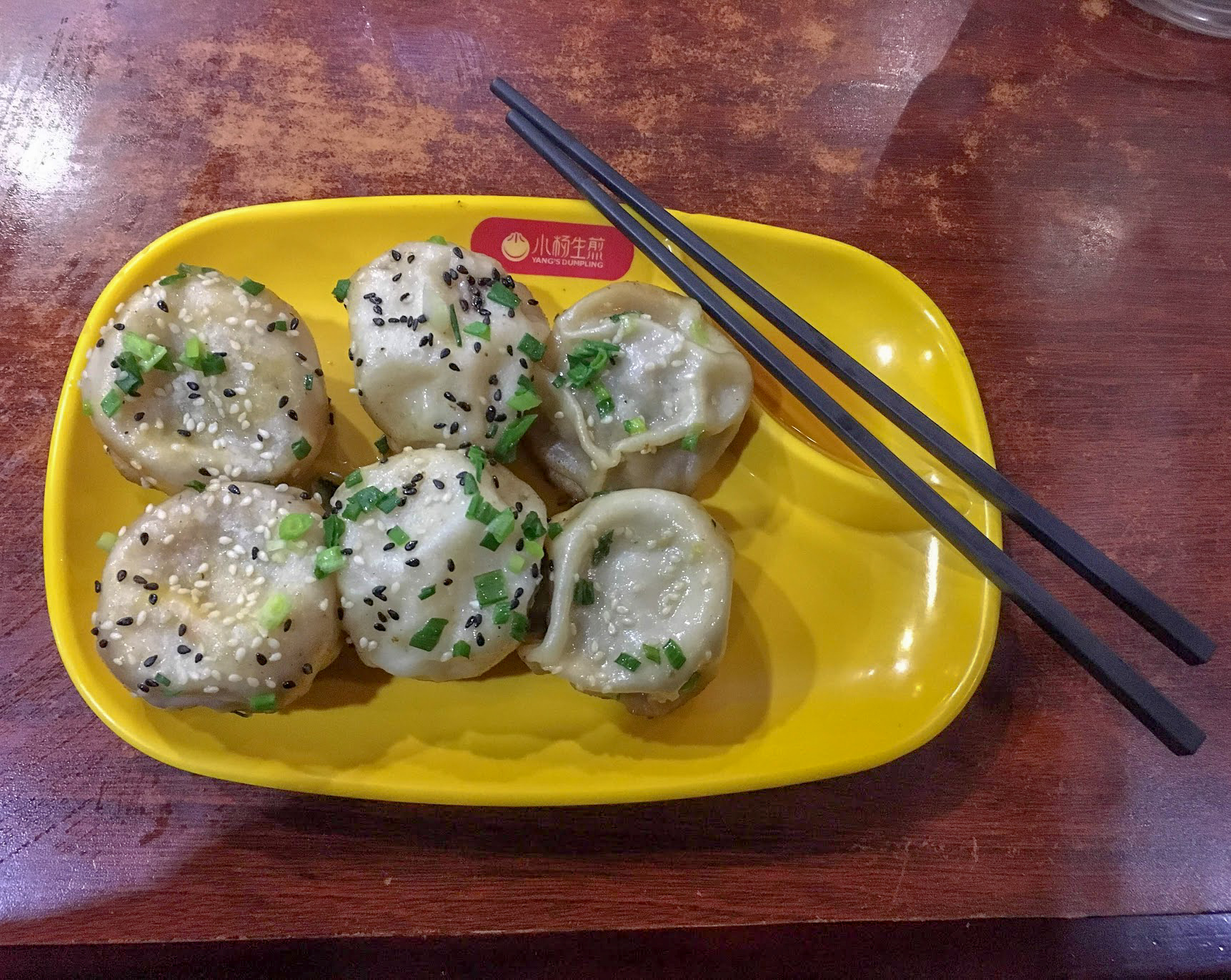 6 steamed dumplings on a yellow plastic plate at Mr Yang's in Shanghai, China