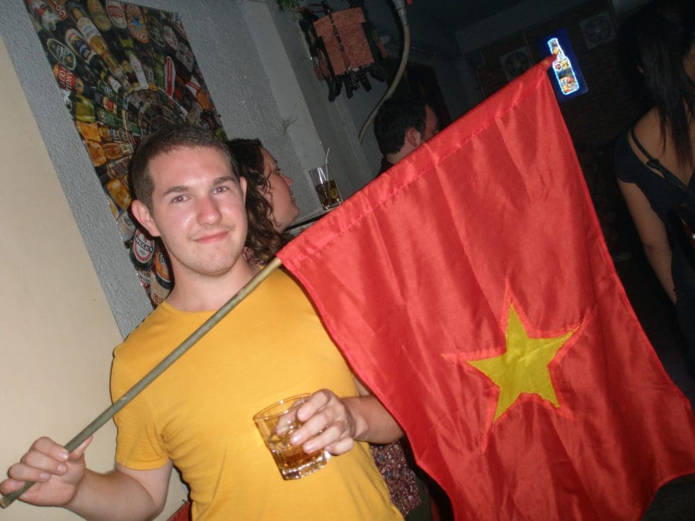 Karl in a yellow t-shirt holding a Vietnamese flag