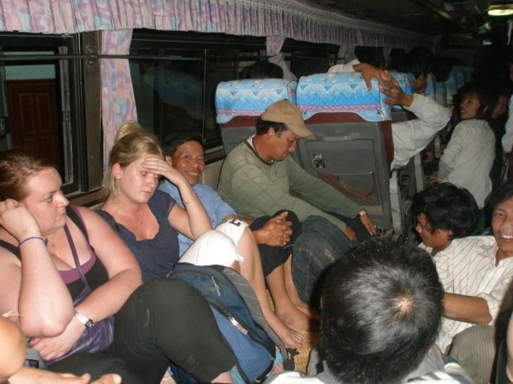 Tourists and locals sit on the floor at the back of a night bus in Vientiane, Laos