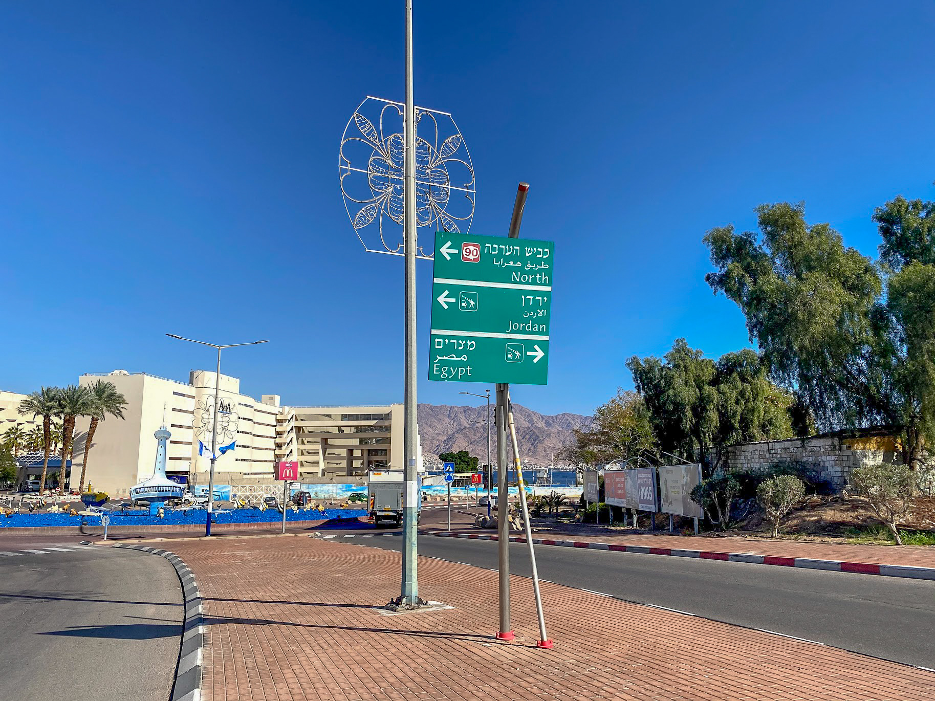 A green direction sign before a roundabout in Eilat, Israel
