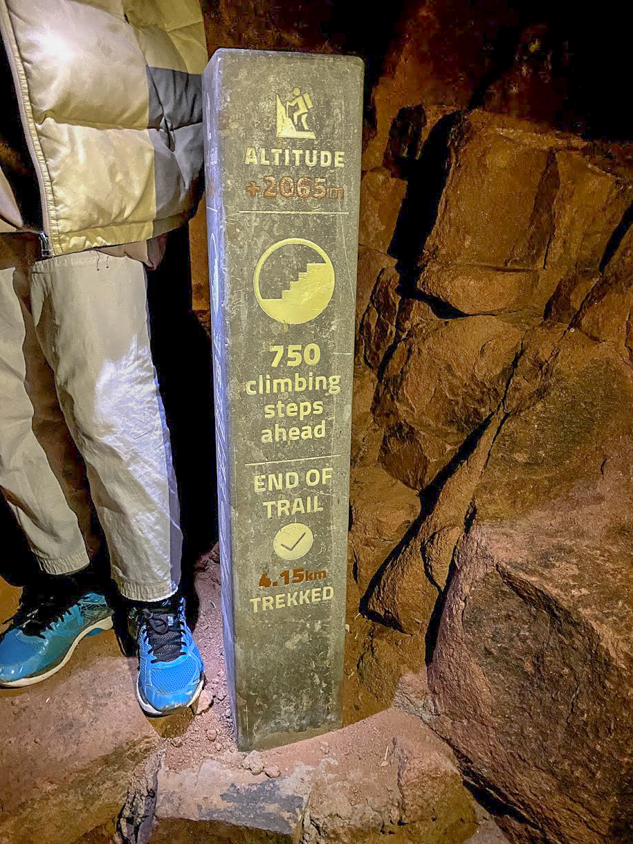 A stone way marker showing an altitude of 2065m, 750 climbing steps ahead and 4.15km trekked on Mount Sinai, Egypt