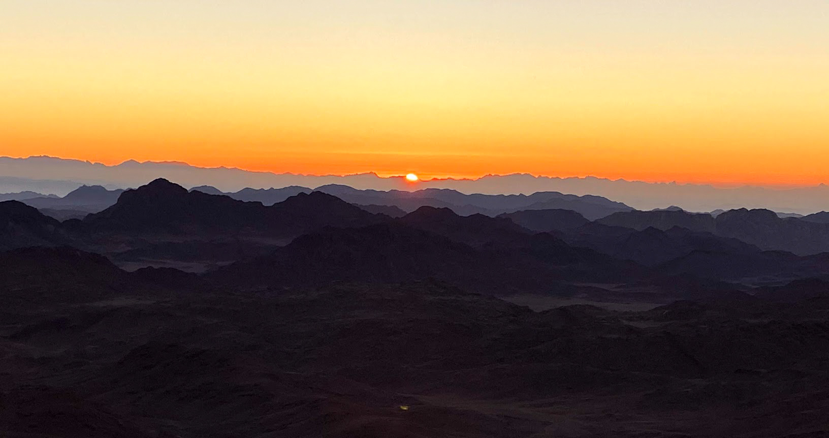 The sun rising over the silhouettes of mountains on Mount Sinai, Egypt