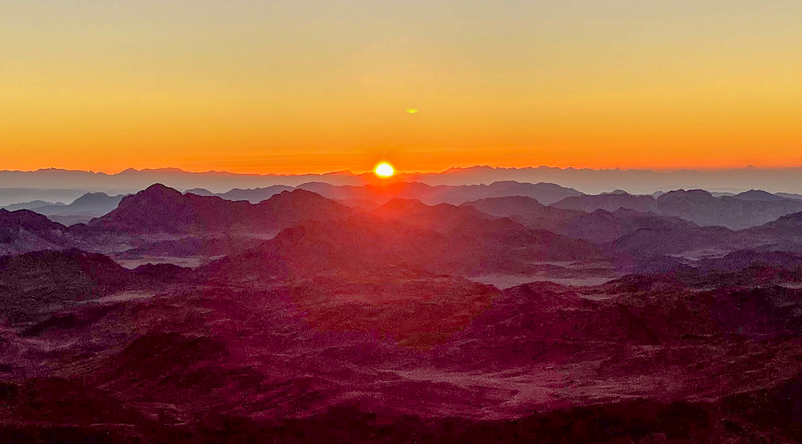 The sun rising over the silhouettes of mountains on Mount Sinai, Egypt