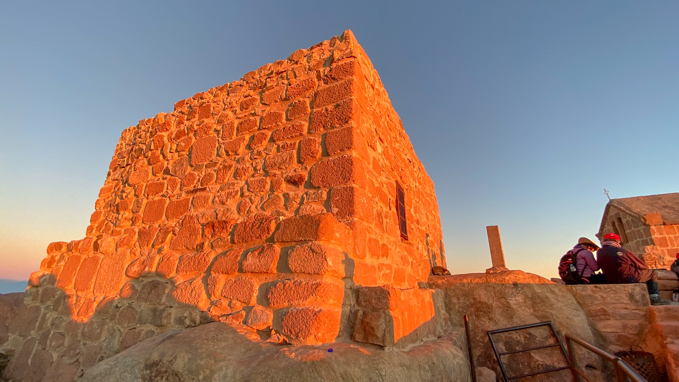 The orange glow of sunrise on a brick wall at the summit of Mount Sinai, Egypt
