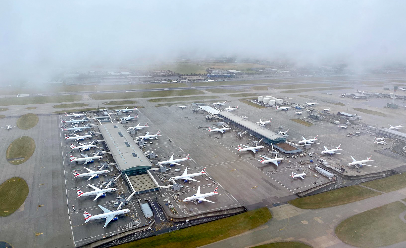 view out of a British Airways plane window of a cloudy Terminal 5 at London Heathrow