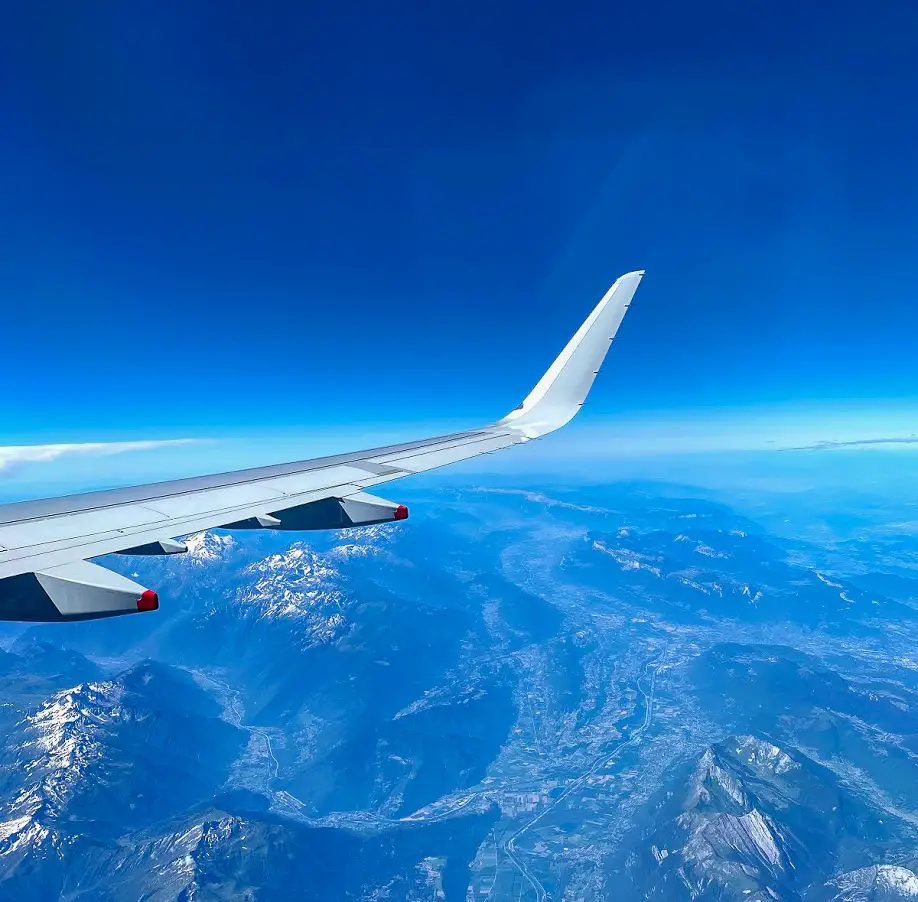 view out of a British Airways plane window of the wing and the Alps below