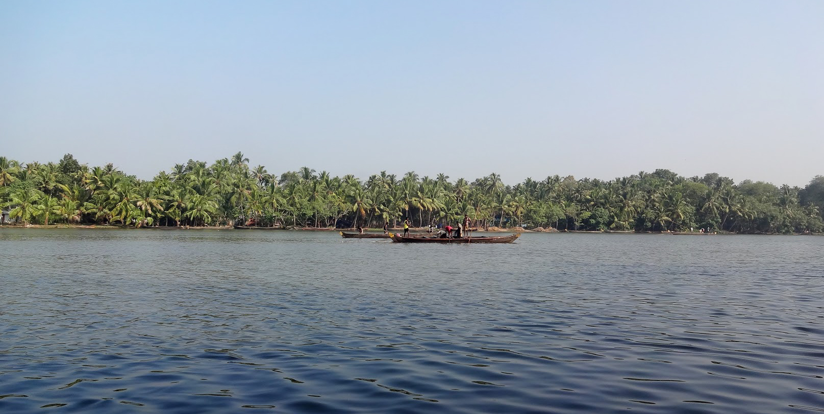 Indian men fishing from wooden boats in the Kappil Backwaters, Kerala, India