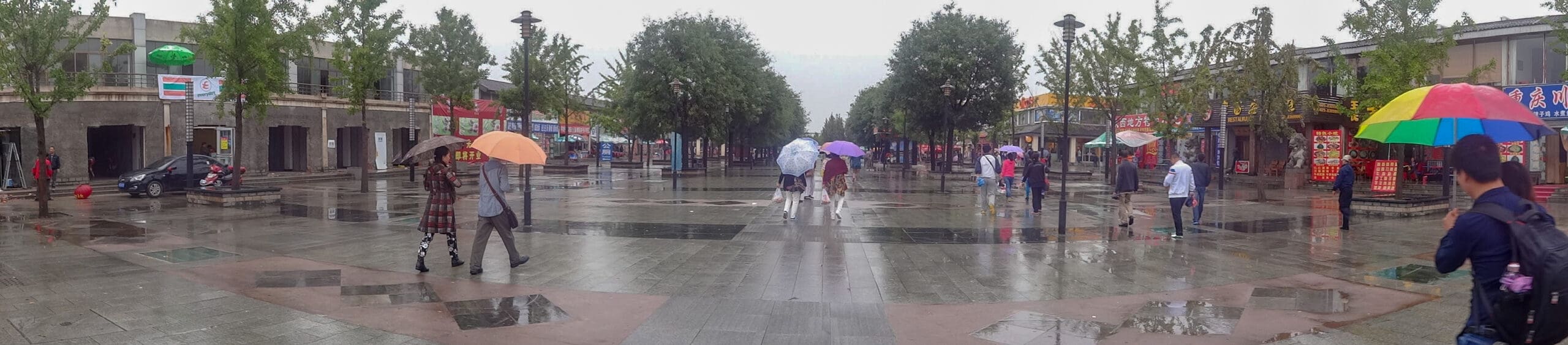 Tourists with umbrellas walk around Emperor Qinshihuang's Mausoleum complex, Xian, China