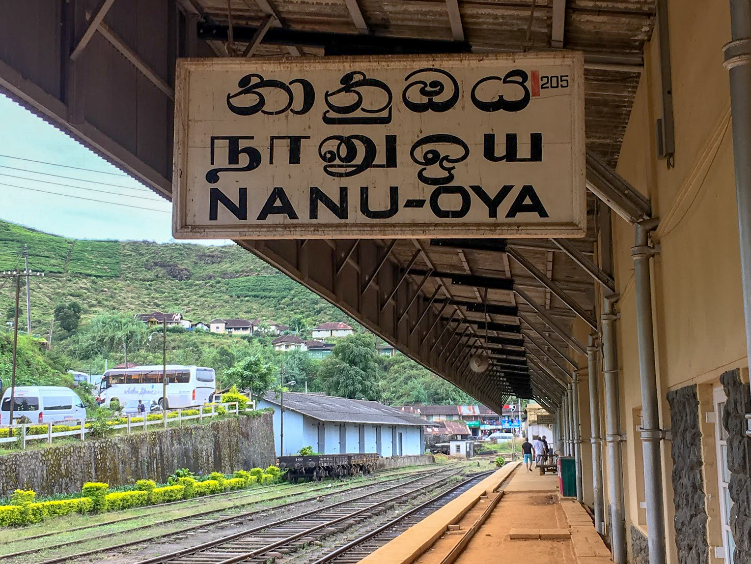 a white sign with black writing Nanu-Oya Nuwara Eliya train station, Sri Lanka